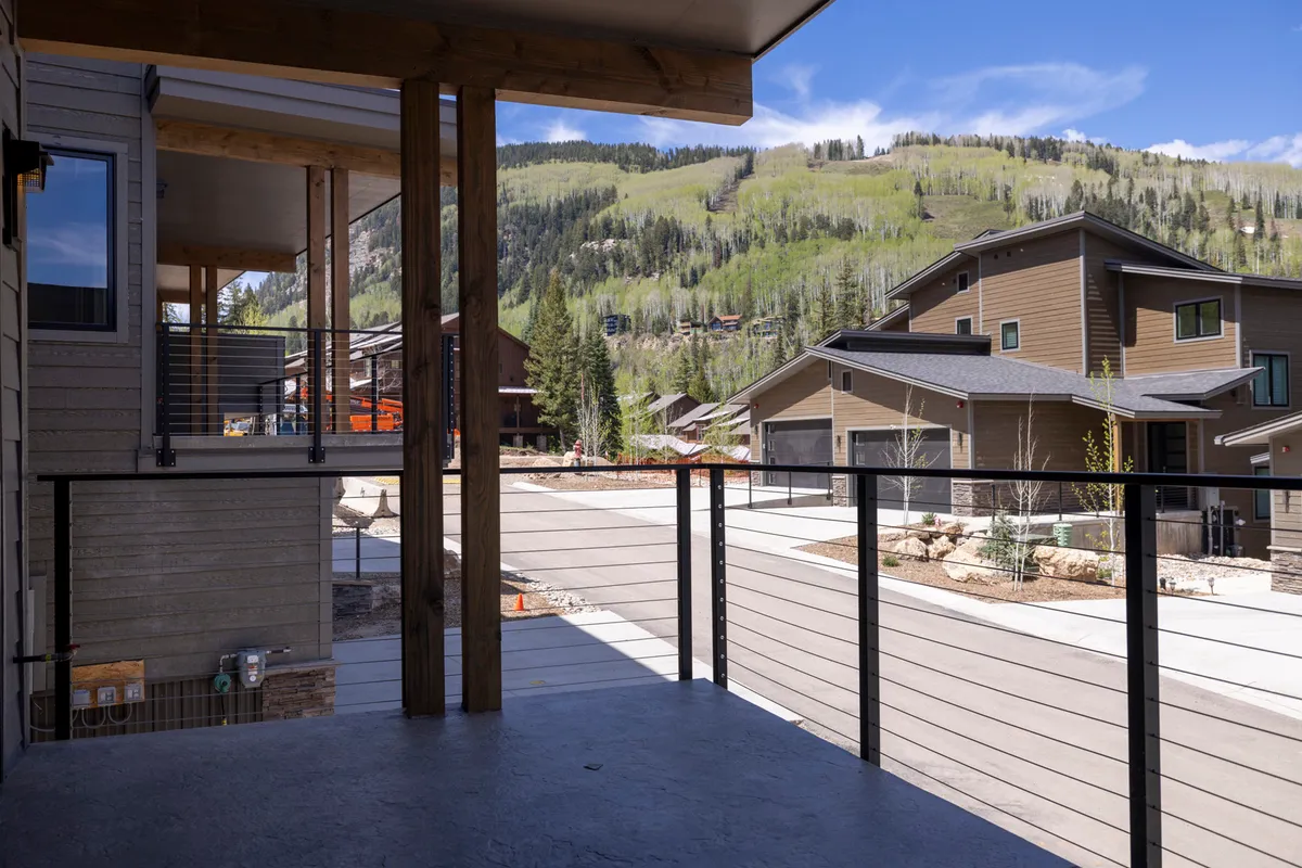 A peaceful exterior view focusing on the balcony, with a beautiful mountain vista in the background and modern architectural lines. The setting is perfect for relaxing, socializing, and enjoying seasonal changes as a group or family.