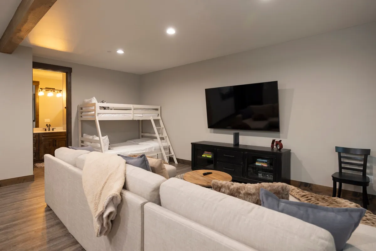 This inviting scene features another angle of the kids’ lounge: bunk beds are visible along one wall, complemented by a TV and a cozy sofa, providing a welcoming spot for kids or teens to relax, socialize, or watch movies together.