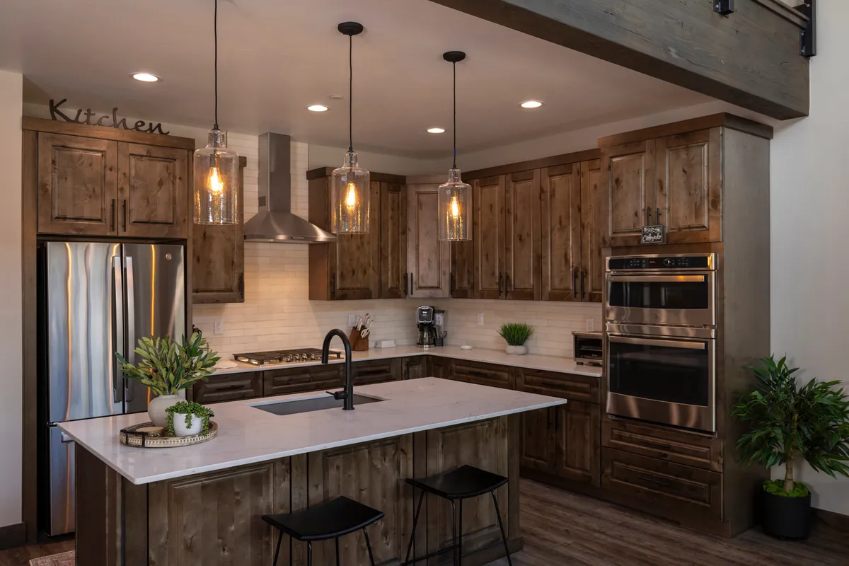A sleek, fully equipped kitchen with a prominent island, modern stainless steel appliances, and glowing pendant lights overhead. This inviting space is designed for cooking and socializing, making it the perfect spot for preparing group meals and sharing stories from the day.